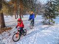 A boy and his father ride bicycles in the park in winter