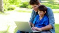 Boy on his fathers tigh using a laptop