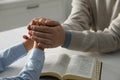 Boy and his godparent praying together at white wooden table indoors, closeup Royalty Free Stock Photo