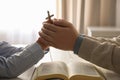 Boy and his godparent praying together at white wooden table indoors, closeup