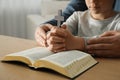 Boy and his godparent praying together at wooden table indoors, closeup Royalty Free Stock Photo
