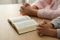 Boy and his godparent praying together at wooden table indoors, closeup Royalty Free Stock Photo