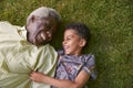 Boy and his granddad lying on grass, overhead close up