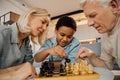 Boy and his grandparents are smiling while playing chess in the living room Royalty Free Stock Photo