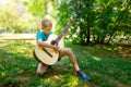 A boy in his hands with a guitar in the park tunes it, but looks at the strings