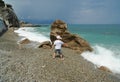 Boy, rocks, pebbles and dialogue with an oncoming wave. Royalty Free Stock Photo