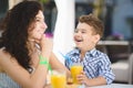 Boy and his mother tasting dessert with juice in resort restaurant outdoor