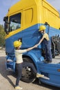 boy with his mother in a yellow construction helmet on a construction site near a yellow-blue truck cab Royalty Free Stock Photo