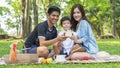 Boy hold money saving house box with mother and father in park.Happy family picnic concept