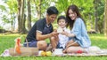 Boy hold money saving house box with mother and father in park.Happy family picnic concept.