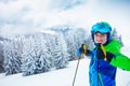 Boy hold poles wearing ski helmet and mask smile stand over firs Royalty Free Stock Photo