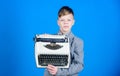 Boy hold retro typewriter on blue background. What to do with this thing. Out of date. I need modern gadget instead this Royalty Free Stock Photo