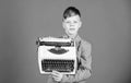 Boy hold retro typewriter on blue background. What to do with this thing. Out of date. I need modern gadget instead this Royalty Free Stock Photo