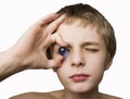 Boy holding blue marble to eye