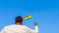 Boy holding Bolivia flag against clear blue sky. Man hand waving Bolivian flag view from back, copy space