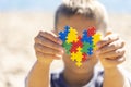 Boy holding colorful puzzle heart in front of his face. World autism awareness day concept