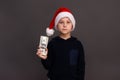 The boy is holding dollars in Santa's helper hat in his hand. on a gray background. mock up Royalty Free Stock Photo