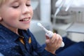 The boy is holding an electric toothbrush. A child learns to brush their teeth.Reception at the children`s dentist. The toothbrus Royalty Free Stock Photo