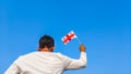 Boy holding Georgia flag against clear blue sky. Man hand waving Georgian flag view from back, copy space