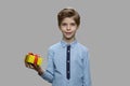 Boy holding gift box on gray background.