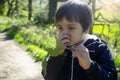 A boy holding green leaf, Child feeling itchy on his nose while walking in the park on Spring or summer, Kid scratching his nose Royalty Free Stock Photo