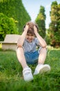 Boy holding his head sitting on the grass Royalty Free Stock Photo