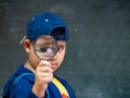 The boy holding the magnifying glass in front of blackboard. Back to School, Education Concept. Royalty Free Stock Photo