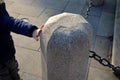 Boy holding a massive stone pillar with a chain on the square. beautifully made stone column with light granite stone profiling
