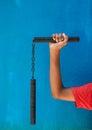 Boy holding Nunchaku on his hand on Blue background. Black nunchaku training for beginner. Hot Tactical Gear Martial Arts