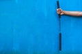 Boy holding Nunchaku on his hand on Blue background. Black nunchaku training for beginner. Hot Tactical Gear Martial Arts