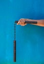 Boy holding Nunchaku on his hand isolated on Blue background. Black nunchaku training for beginner. Hot Tactical Gear Martial Arts