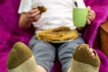 The guy with the torn sock is sitting in a chair with a plate of pancakes and a mug of tea. Royalty Free Stock Photo