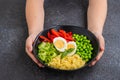 The boy is holding a salad bowl with green peas, millet, sweet pepper, fresh cucumber and boiled egg Royalty Free Stock Photo