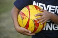 Boy holding a soccer ball in his arms. Close up. Play soccer. Sport. Childhood. Old yellow and red ball very used. Fun, summer, va