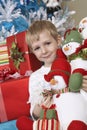 Boy Holding Stuffed Snowman In Front Of Christmas Tree