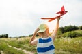 Boy holding toy airplane and hat preparing to launch plane into the sky outdoors. Royalty Free Stock Photo