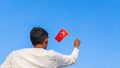 Boy holding Turkey flag against clear blue sky. Man hand waving Turkish flag view from back, copy space