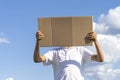 Boy holding with two hands brown paper cardboard outdoors with blue sky background Royalty Free Stock Photo