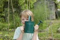 Boy Holding Watering Can In Garden