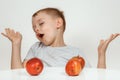 Boy holds a apples, healthy food and vitamins, smiling, white background. Joyful boy with a red apple on an isolated Royalty Free Stock Photo