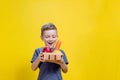 The boy holds a basket with fresh vegetables and fruits on a yellow background. Vegan and healthy concept