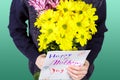 Boy holds a bouquet of yellow and pink chrysanthemums and handmade greeting card Happy Mother`s day in his hands. Flowers and gift Royalty Free Stock Photo