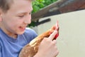 The boy holds a brown chicken in his hands and smiles and kisses her and hugs and holds a finger for his beak Royalty Free Stock Photo
