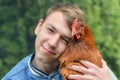 The boy holds a chicken in his hands and hugs her Royalty Free Stock Photo