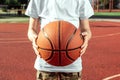 The boy holds in his hands a basketball closeup, against the background of a basketball court. The concept of a sports lifestyle, Royalty Free Stock Photo