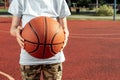 The boy holds in his hands a basketball closeup, against the background of a basketball court. The concept of a sports lifestyle, Royalty Free Stock Photo
