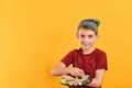 The boy holds a palette with paints and a brush in his hands, a child artist in a hat on a yellow background Royalty Free Stock Photo