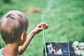 Boy holds smoking green stick near grill with cooking meat