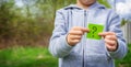 the boy holds stickers with a question mark on the background of the park. selective focus Royalty Free Stock Photo