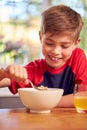 Boy At Home Eating Bowl Of Breakfast Cereal At Kitchen Counter Royalty Free Stock Photo